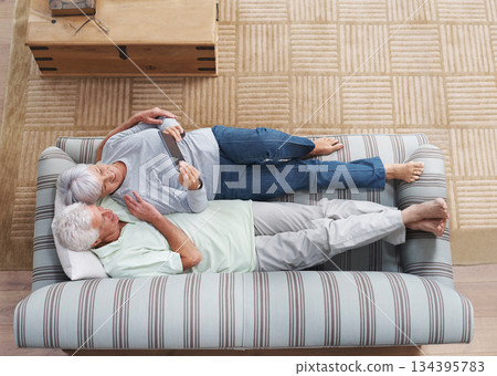 Top view, senior couple and sofa with tablet, social media, online news app and ebook in lounge. Happy old man, woman and relax with digital technology, subscription or website on internet connection Top view, senior couple and sofa with tablet, social media, online news app and ebook in lounge. Happy old man, woman and relax with digital technology, subscription or website on internet connection 134395783