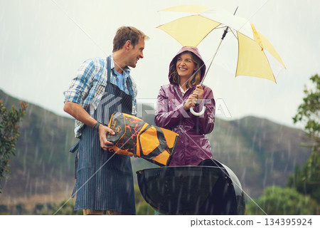 Man, woman and barbecue in rain with umbrella, charcoal or surprise on vacation with love in garden. Couple, outdoor and grill in storm, backyard or cooking in winter with helping hand, wind or smile Man, woman and barbecue in rain with umbrella, charcoal or surprise on vacation with love in garden. Couple, outdoor and grill in storm, backyard or cooking in winter with helping hand, wind or smile 134395924