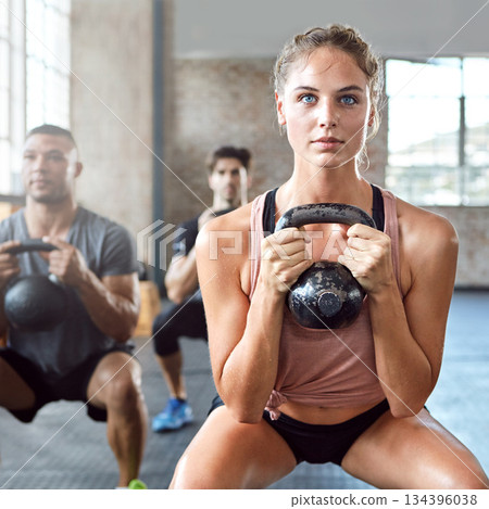 Sports, kettlebell and woman doing a workout with a group for strength training in a gym. Fitness, energy and female athlete doing a exercise challenge with weights with people in a wellness center. 134396038