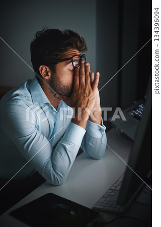 Stress, night and a businessman with a headache at work, deadline burnout and frustrated. Sad, problem and a corporate employee in a dark office with anxiety or depression from an email on a pc 134396094