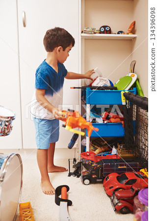 Home, toys and boy playing, relax and learning with development, happiness and organized. Male child, kid or young person with games, playful and growth in a room, cleaning or creativity in a bedroom 134396098