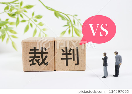 Two miniature male figures in conflict with wooden blocks representing a trial 134397065