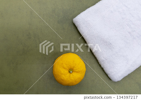 A single yuzu and a white towel placed on a green background. Image of a yuzu bath or bathing on the winter solstice. 134397217