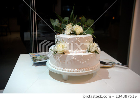 Wedding cake with white roses on a white table under the moon Wedding cake with white roses on a white table under the moon 134397519