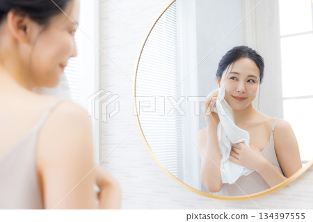 Young woman looking in the mirror in the bathroom 134397555