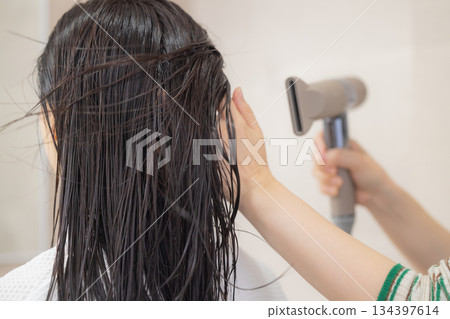 年輕女子正在用吹風機吹乾頭髮 134397614