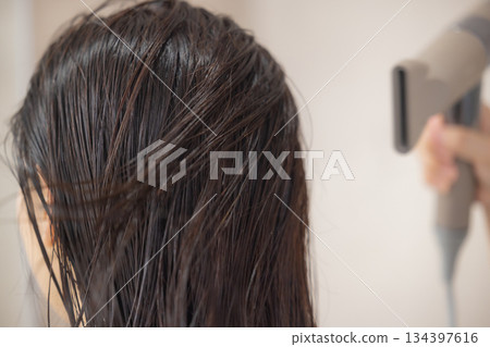 年輕女子正在用吹風機吹乾頭髮 134397616