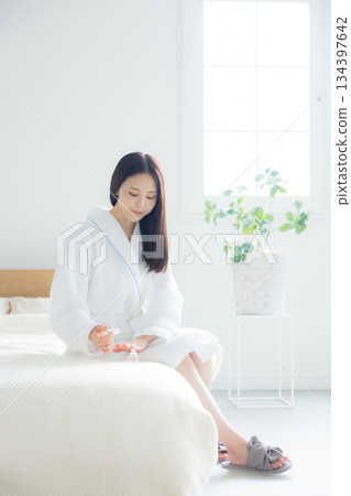 A woman sitting on a bed A woman sitting on a bed 134397642