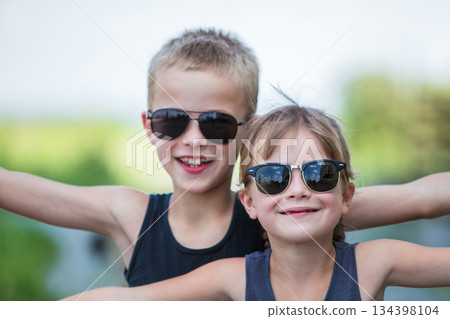 Two children in black sunglasses having fun time outdoors in summer. Two children in black sunglasses having fun time outdoors in summer. 134398104