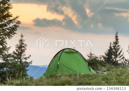 Small tourist tent on grassy mountain hill. Summer camping in mountains at dawn. Tourism concept. Small tourist tent on grassy mountain hill. Summer camping in mountains at dawn. Tourism concept. 134398113