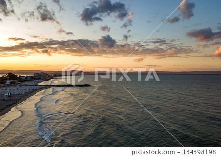 Sea surface with blue water waves under yellow and purple sunset sky. 134398198