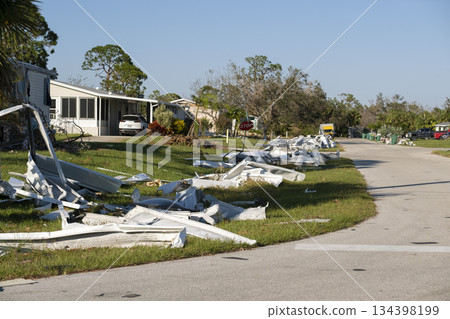 Scrap metal disposed in heaps on street side after hurricane severely damaged houses in Florida mobile home residential area. Consequences of natural disaster 134398199