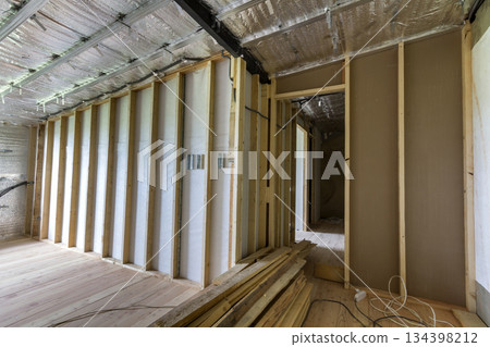 Room under construction and renovation with silver aluminum foil on walls and ceiling, oak floor and wooden timber frame for future partition wall. Professional reconstruction and insulation concept. 134398212