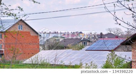 Residential house with solar photovoltaic panels for producing of clean ecological electrical energy mounted on backyard ground in suburban rural area. Concept of autonomous home Residential house with solar photovoltaic panels for producing of clean ecological electrical energy mounted on backyard ground in suburban rural area. Concept of autonomous home 134398220