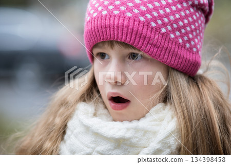 Pretty child girl in warm knitted winter clothes outdoors. 134398458