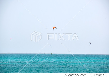 People sportsmen windsurfing and kite surfing in blue ocean water. Summer extreme exotic sport concept 134398548