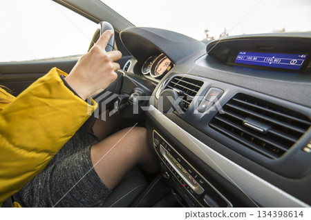 Modern car interior with driver female hands on steering wheel. Safe driving concept. Modern car interior with driver female hands on steering wheel. Safe driving concept. 134398614