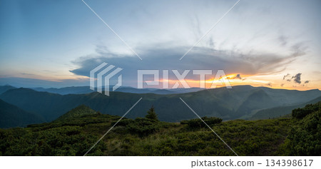 Misty evening over high mountain peaks and distant valley at bright sunset. Amazingl scenery of wild hillside at dusk 134398617