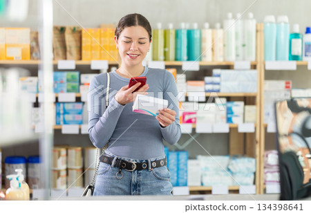 Young girl customer scanning QR-code on pills box Young girl customer scanning QR-code on pills box 134398641