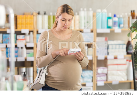 Pregnant woman chooses pills at pharmacy Pregnant woman chooses pills at pharmacy 134398683