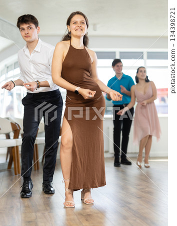 Couple in evening dresses enjoys pair dance boogie-woogie, interacting with each other on floor Couple in evening dresses enjoys pair dance boogie-woogie, interacting with each other on floor 134398721