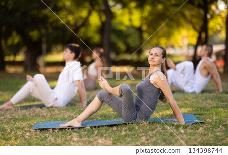 Woman performing yoga asanas during group session in park Woman performing yoga asanas during group session in park 134398744