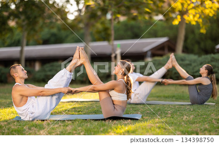Guy and girl practice pair yoga doing Buddy boat pose asana Guy and girl practice pair yoga doing Buddy boat pose asana 134398750