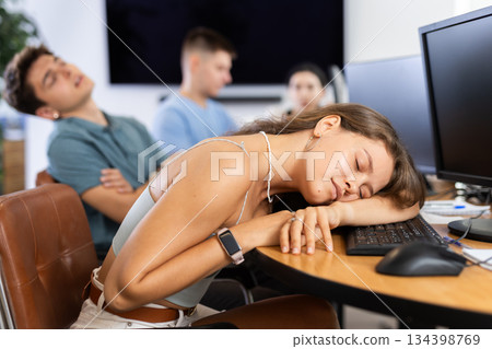 Exhausted young female student sleeping at table in computer classroom Exhausted young female student sleeping at table in computer classroom 134398769