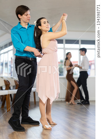 Girl and guy enjoying passionate latin american dancing with male partner in dance hall 134398771