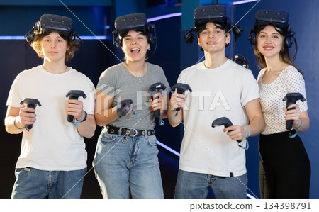 Friends in virtual reality glasses holding joysticks after playing virtual games 134398791