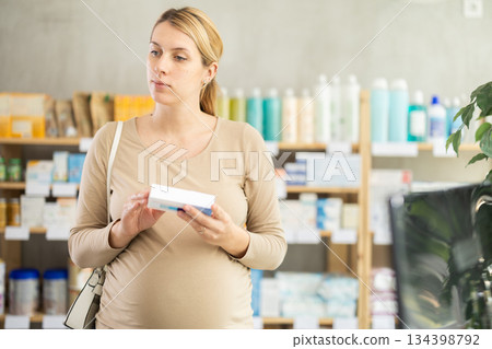 Pregnant woman chooses pills at pharmacy 134398792