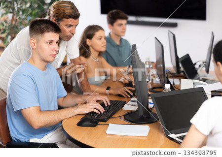 During computer lesson, male teacher helps guy student complete difficult task, During computer lesson, male teacher helps guy student complete difficult task, 134398795