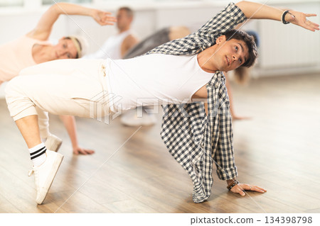 Man and his students perform hip hop dance on one bent leg, movement in horizontal plane near floor Man and his students perform hip hop dance on one bent leg, movement in horizontal plane near floor 134398798
