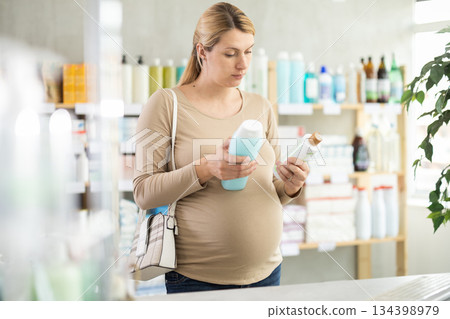 Pregnant woman choose antidandruff shampoo in pharmacy Pregnant woman choose antidandruff shampoo in pharmacy 134398979