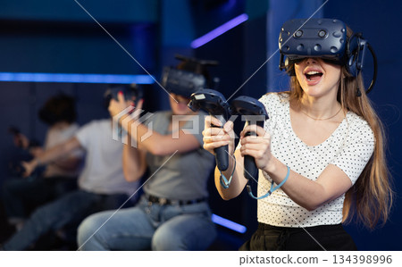 Emotional girl in virtual glasses plays a game by controlling joysticks Emotional girl in virtual glasses plays a game by controlling joysticks 134398996