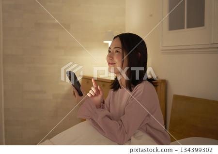 A woman imagining in bed with a smartphone 134399302