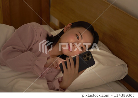 A woman using a smartphone in bed 134399305