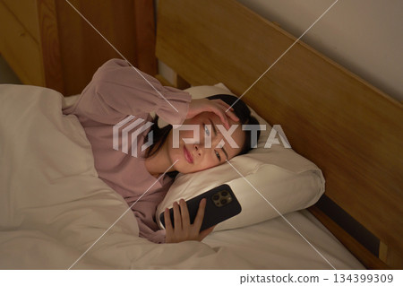 Woman looking at smartphone in futon Woman looking at smartphone in futon 134399309