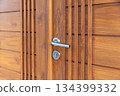 Stainless steel door handle on wooden door. 134399332