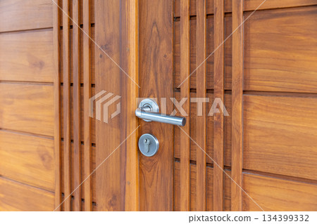 Stainless steel door handle on wooden door. Stainless steel door handle on wooden door. 134399332