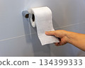 Close up of woman hand pulling toilet paper in holder. 134399333