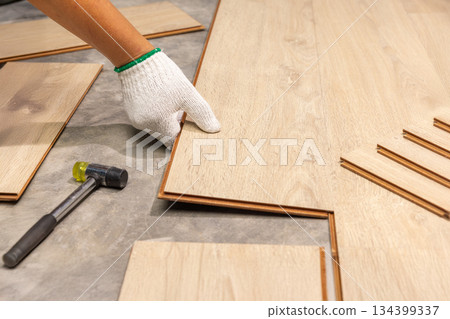 Worker Installing Interlocking laminate floor, home renovation. Worker Installing Interlocking laminate floor, home renovation. 134399337