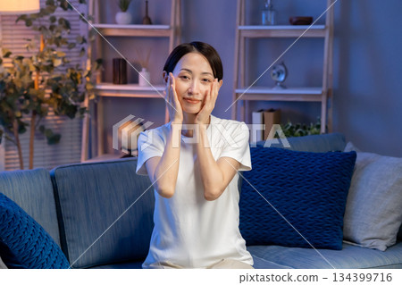 A woman doing skin care in the living room 134399716
