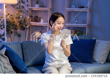 一位女子對著手鏡微笑 134399718