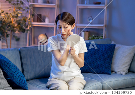 A woman troubled watching a mirror 134399720