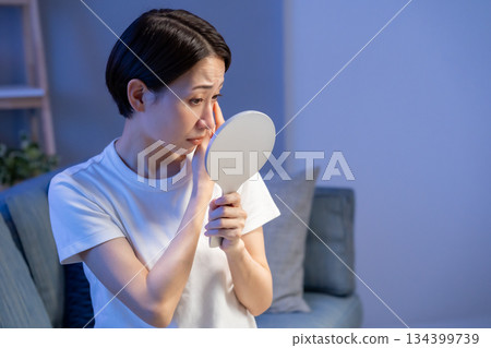 A woman troubled by looking at the hand mirror 134399739