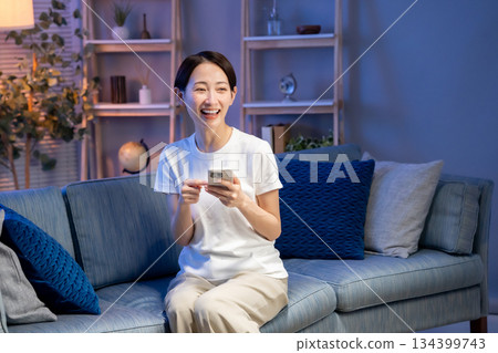 一個女人在客廳裡看著她的智能手機 134399743