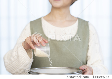 Hands of a senior woman preparing to cook rice in the kitchen 134399783