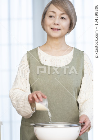 一位老婦人在廚房準備煮飯。 134399806