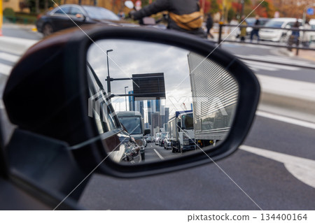 A line of cars and buildings reflected in the driver's side mirror 134400164